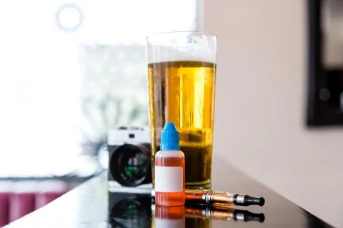 Digital camera, beer and vaping equipment Stock Photos