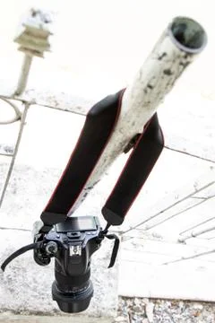 The digital camera hangs on the strap on the white rail. Stock Photos