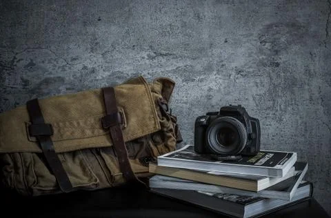 Digital camera on top of stacking books and messenger bag Stock Photos