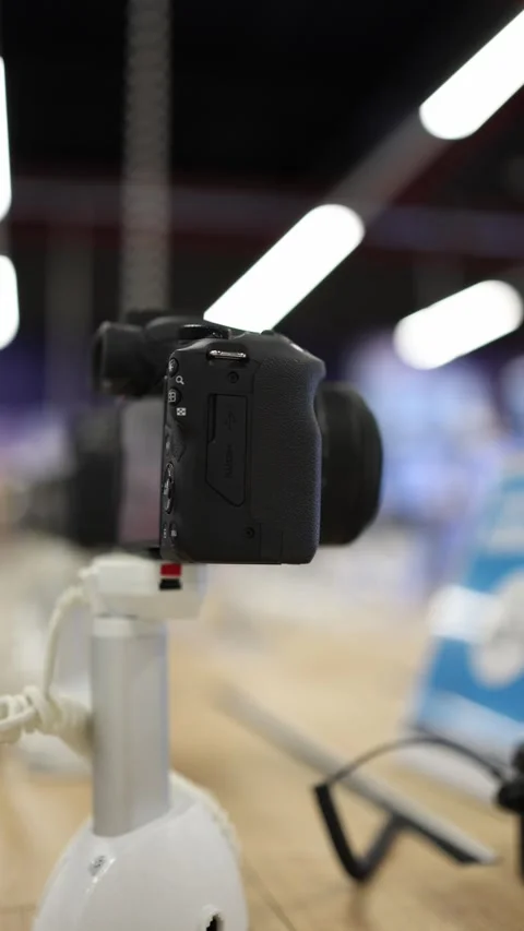Digital camera with zoom lens displayed on stand in modern electronics store Stock Footage 345357359
