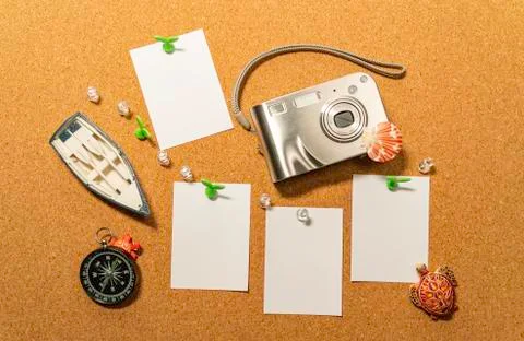 Digital compact camera on cork board with blank white paper, compass and boat Stock-Fotos