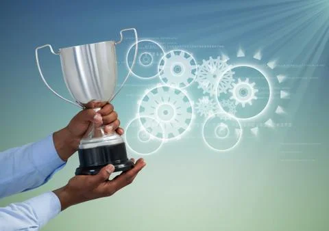 Digital composite image of hand holding trophy against gears 写真素材