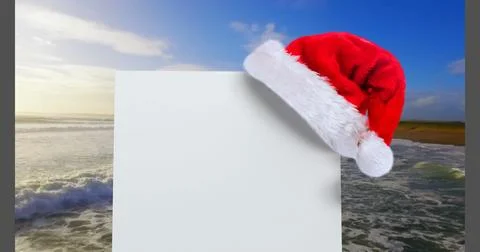 Digital composite of Santa hat with white card and sea Stock Photos