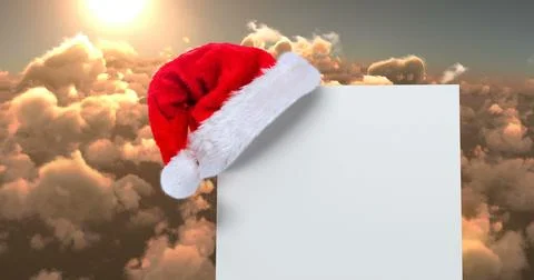 Digital composite of Santa hat with white card and clouds 스톡 사진