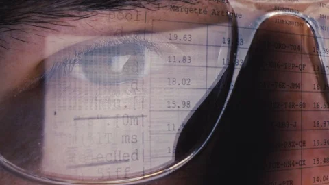 Digital computer code on a screen is reflected in the glasses of a working Stock Footage 124733115