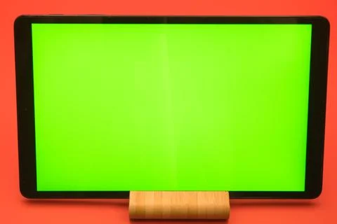 Digital display with green screen background on wooden stand against red wall Stock Photos
