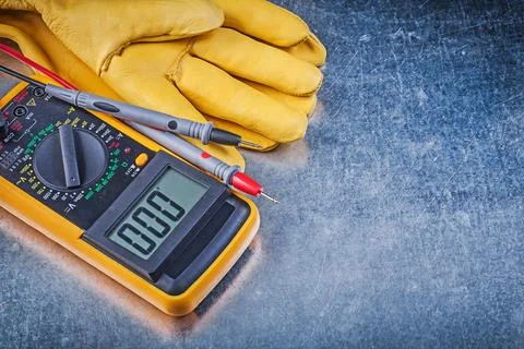 Digital electrical tester Test leads Pair of safety gloves on metallic Stock Photos