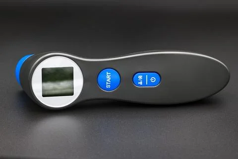 Digital forehead thermometer with LCD display on dark background Stock Photos