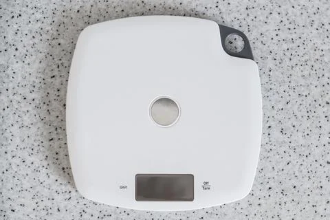 Digital kitchen scale on a kitchen table. Top view on electronic scales for Stock Photos