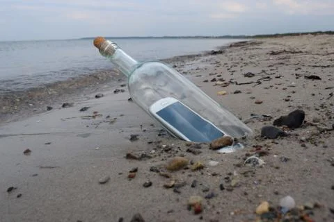 Digital native castaway sending a help message in a bottle Stock Photos