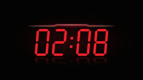 Digital neon red clock displaying 24 hour time on dark background. 4K Video stock 346882330