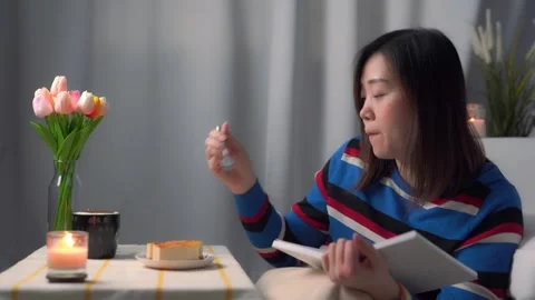 Digital nomad concept asian freelancer woman during read book and eat cake Stock Footage 256202150