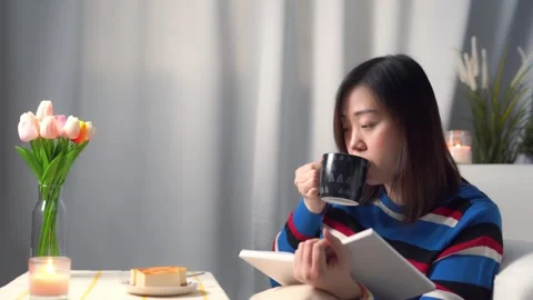 Digital nomad concept asian freelancer woman during read book and eat cake Stock Footage 256202154