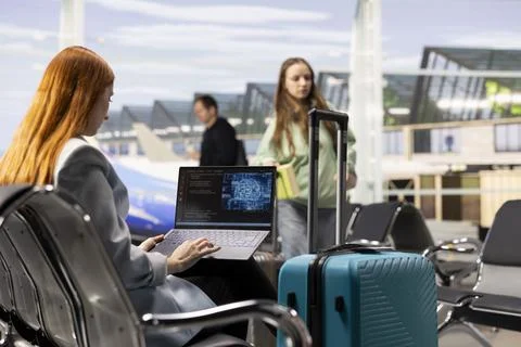 Digital nomad girl coding with AI system in airport terminal 스톡 사진
