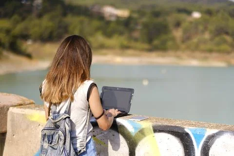 Digital nomad. Girl working with the computer in a natural setting. Stock Photos