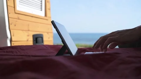Digital nomad hands typing on tablet inside van with sea view Stock Footage 334281482