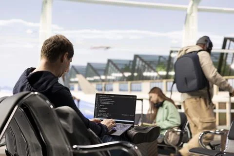 Digital nomad man programming on laptop in international airport Stock Photos