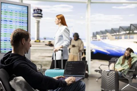 Digital nomad man programming on laptop in international airport 库存照片
