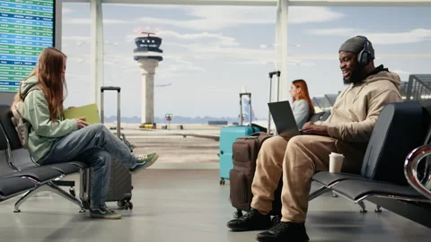 Digital nomad participating in online video call in airport terminal lounge Stock Footage 333167537
