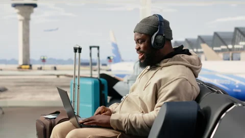 Digital nomad participating in online video call in airport terminal lounge Stock Footage 333171390