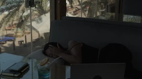 Digital nomad sleeping after work in tropical cafe as camera reveals ocean Stock Footage 346252121