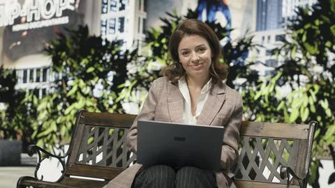 Digital nomad using laptop on park bench for remote work Stock Photos