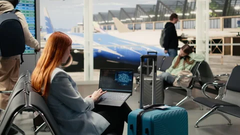 Digital nomad woman coding with AI system in airport terminal Stock Footage 333167820