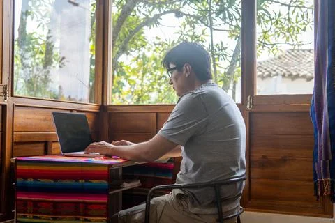 Digital nomad working in a cabin by the window typing on a laptop Stock Photos