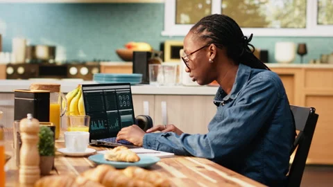 Digital nomad writing research data from charts, laptop displaying analytics Stock Footage 344247413
