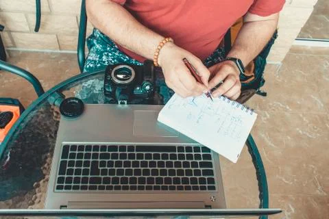 Digital nomadic man taking notes in a notebook. Stock Photos
