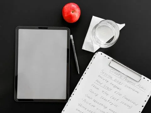 Digital notetaking setup with tablet, red apple, and clipboard on desk Stock Photos