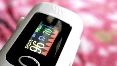 A digital oximeter reading of a person oxygen level and pulse rate which is fluc Stock Footage 246403864