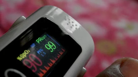 A digital oximeter reading of a person oxygen level and pulse rate which is fluc Stock Footage 246403924