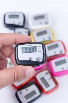 Digital pedometer in the hand over pile of pedometers Stock Photos