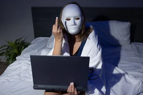 Digital Privacy Risks Illustrated by Masked Figure in Bed With Laptop at Night Stock Photos