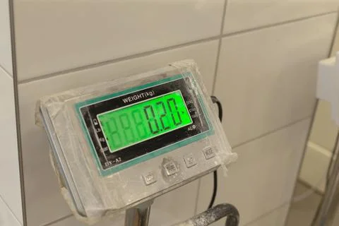Digital scale display showing zero weight in dusty tiled room with worn casing Stock Photos
