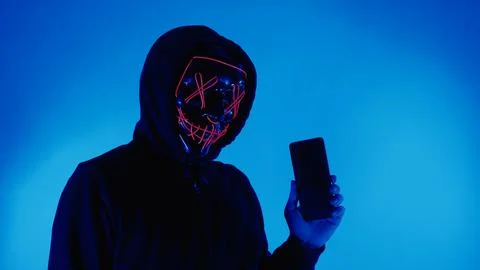 Digital security Concept. Anonymous hacker with mask holding smartphone hacke Stock Photos