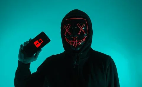 Digital security Concept. Anonymous hacker with mask holding smartphone hacke Stock Photos