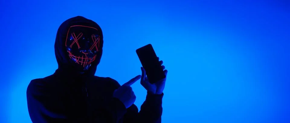 Digital security Concept. Anonymous hacker with mask holding smartphone hacke Stock Photos