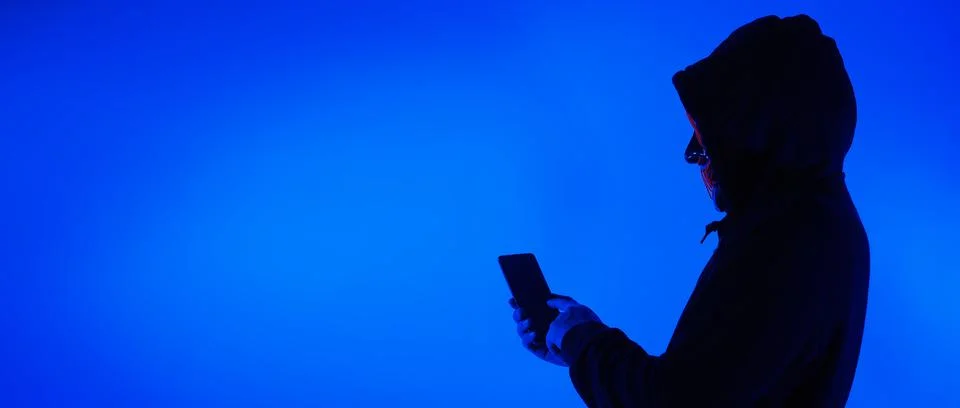 Digital security Concept. Anonymous hacker with mask holding smartphone hacke Stock Photos