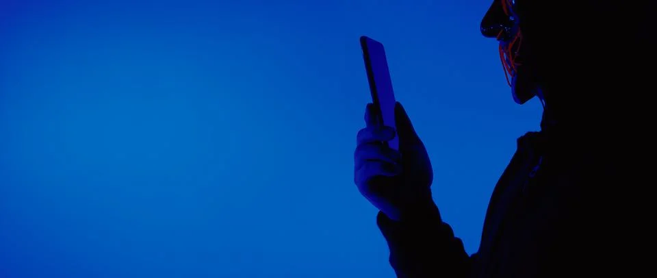 Digital security Concept. Anonymous hacker with mask holding smartphone hacke Stock Photos