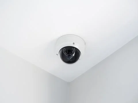 Digital security eye. A white round indoor CCTV surveillance camera monitorin Stock Photos