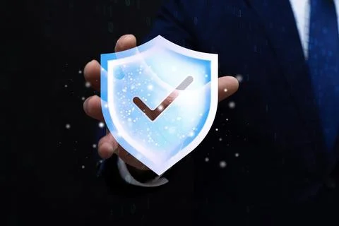 Digital security shield with check mark above businessman hand on dark bina.. Stock Photos