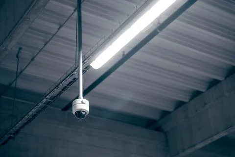 Digital surveillance camera on the ceiling in a warehouse room Stock Photos