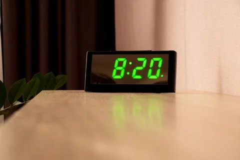 A digital table clock stands on the table in the apartment during the day Stock Photos