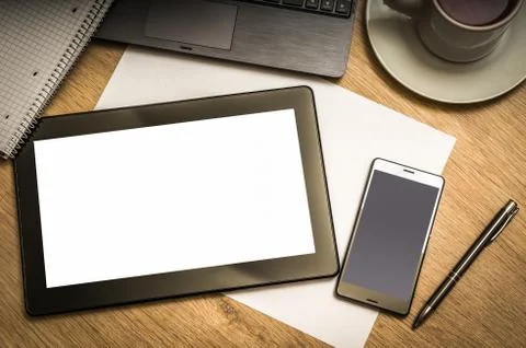 Digital tablet with blank screen and mobile phone on wooden table in office Stock Photos