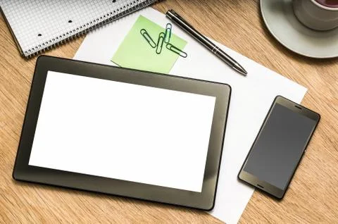 Digital tablet with blank screen and mobile phone on wooden table in office Stock Photos