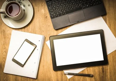 Digital tablet with blank screen and mobile phone on wooden table in office Stock Photos