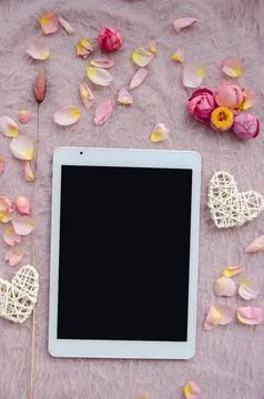Digital tablet, blank screen with small petals and white tangled hearts Stock Photos