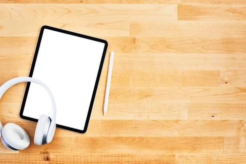 Digital tablet with blank white screen, pen and wireless headphone on wooden  스톡 사진